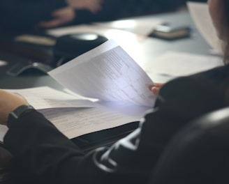 a woman sitting at a table reading a paper